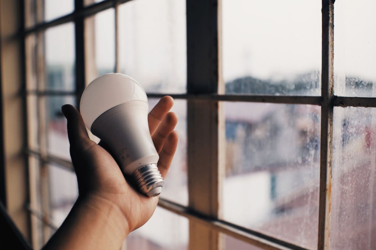 Energiesparen leicht gemacht: Ratgeber für Haushalte 2025 Eine Hand hält eine LED-Glühbirne nahe einem Fenster und symbolisiert Energieeffizienz.