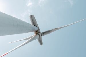 Blick auf eine majestätische Windturbine unter einem klaren blauen Himmel, die Innovationen im Bereich erneuerbare Energien