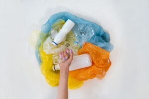Eine Hand, die einen Haufen Plastikmüll vor einem weißen Hintergrund hält und Recycling betont.