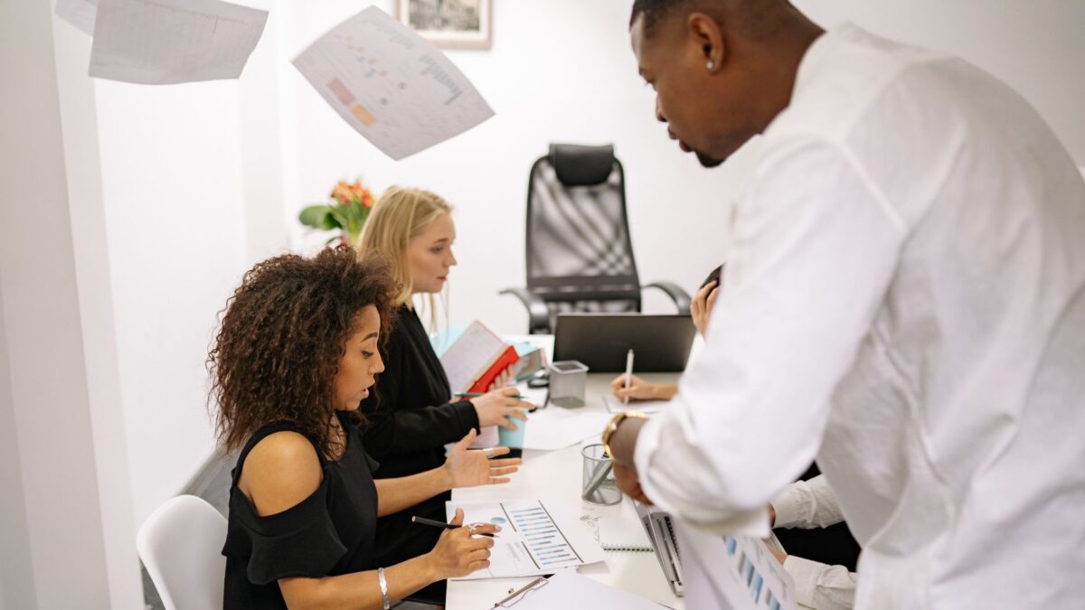 A diverse group of adults engaged in a collaborative office meeting with documents on the table.