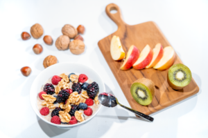 Eine nahrhafte Frühstücksschüssel mit frischen Beeren und Walnüssen, serviert mit geschnittenem Obst und Kiwi.