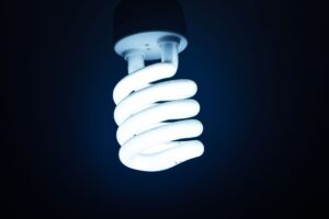 Nahaufnahme einer leuchtenden Spiral-Energiesparlampe vor dunklem Hintergrund, die nachhaltige Energie betont.