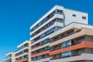 Moderne, mehrstöckige Wohnhäuser mit Balkonen unter strahlend blauem Himmel präsentieren zeitgenössische Architektur.