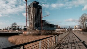 Ein im Bau befindliches Hochhaus in Hamburg, das moderne Architektur mit Kränen und umgebender Infrastruktur zeigt.
