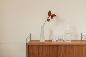 Eine ruhige minimalistische Anordnung mit einer Keramikvase und Gläsern auf einem Holztisch.